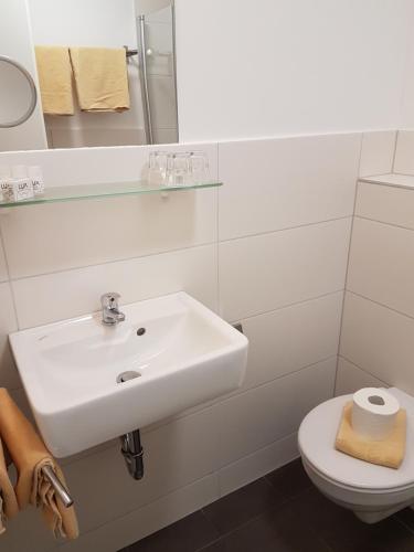 a white bathroom with a sink and a toilet at Hotel Scheffelhof in Konstanz