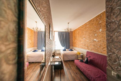 um quarto de hotel com duas camas e um sofá vermelho em Avangard Hotel em São Petersburgo