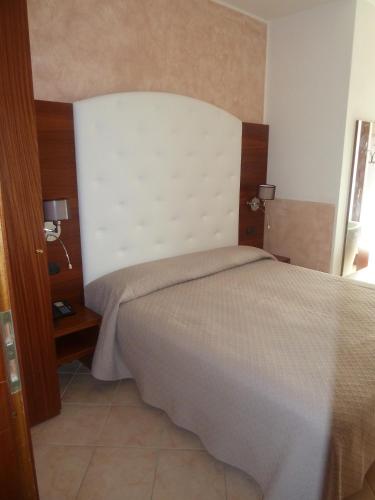 a bedroom with a bed with a white headboard at Albergo Casa Este in Brenzone sul Garda