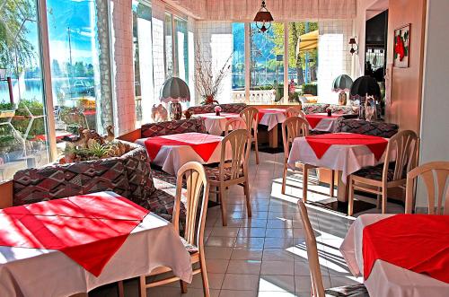 a restaurant with tables and chairs with red napkins at Hotel La Piroga in Calceranica al Lago