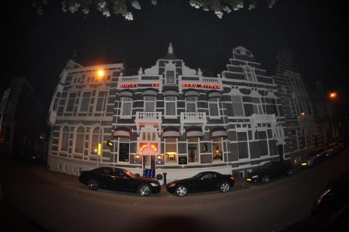 cars parked in front of a tall building at Budget Hotel Le Beau Rivage in Middelburg