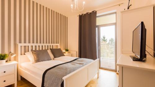 Schlafzimmer mit einem Bett, einem TV und einem Fenster in der Unterkunft VacationClub - Diune Apartment 50 in Kołobrzeg