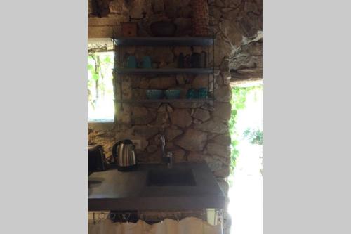 une cuisine avec un évier et un mur en pierre dans l'établissement Chez Caro, à Corbara