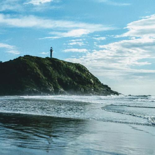 a lighthouse sitting on top of a hill next to the ocean at Pousada das Gêmeas in Ilha do Mel