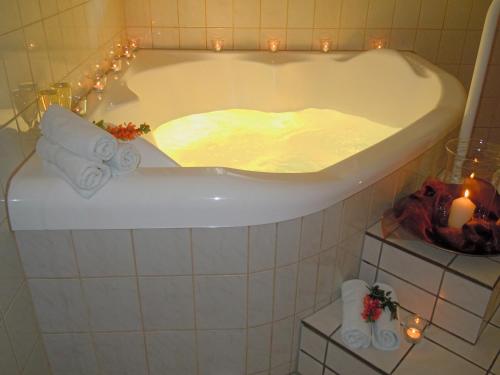 een badkamer met een bad met kaarsen en verlichting bij Hotel Lugerhof in Weiding