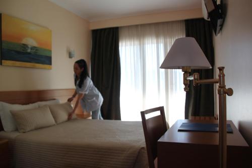 a woman standing next to a bed in a hotel room at Hotel Quasar in Porto