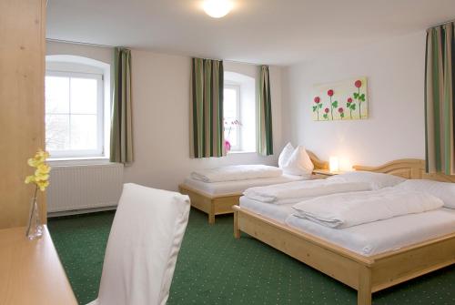 two beds in a room with green floors and windows at Hotel Alt-Oberndorf in Oberndorf bei Salzburg