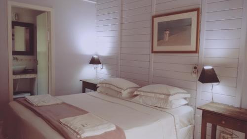 a white bedroom with a bed with two pillows at Pousada das Gêmeas in Ilha do Mel