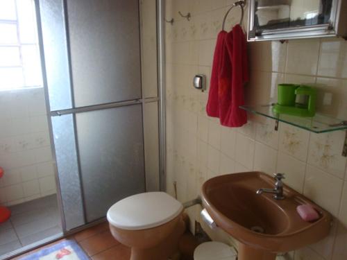 uma casa de banho com um chuveiro, um WC e um lavatório. em Suíte Aconchegante em Caraguatatuba