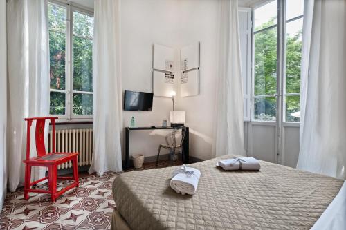 a bedroom with a bed and a red chair and windows at Lucca in Villa Lucrezia in Lucca