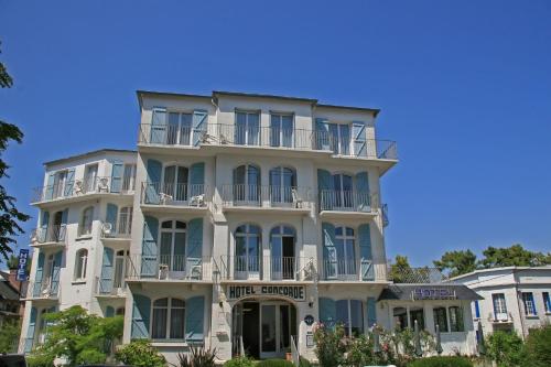 un grand bâtiment blanc avec des balcons dans l'établissement Hôtel La Concorde, à La Baule