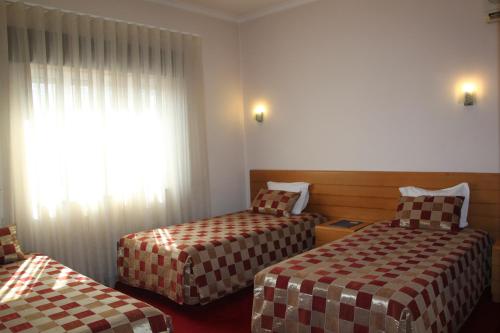 a hotel room with two beds and a window at Hotel Quasar in Porto
