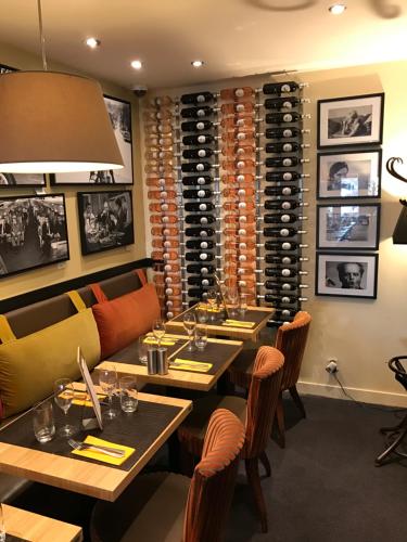 a restaurant with tables and chairs and a wine cellar at Hotel l'Avenue in Chantilly