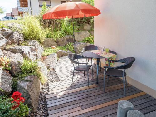 - une table et des chaises sur une terrasse en bois avec un parasol dans l'établissement Apartment in Rickenbach near the Swiss Alps, à Rickenbach