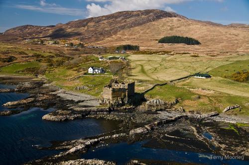 an old castle on a hill next to a body of water at Mingary Castle - Restaurant with Rooms in Kilchoan