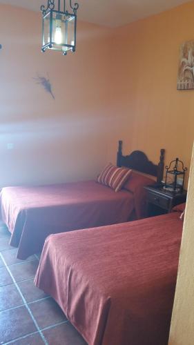 a room with two beds with red sheets on them at Hotel Restaurante Atalaya in Comares