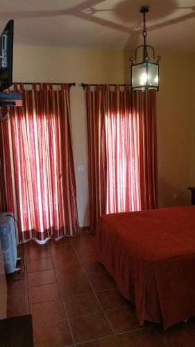 a bedroom with red curtains and a bed in a room at Hotel Restaurante Atalaya in Comares