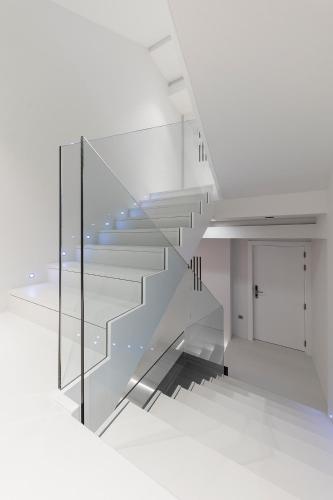 a staircase with glass railing in a white room at Hotel U Viveiro in Viveiro