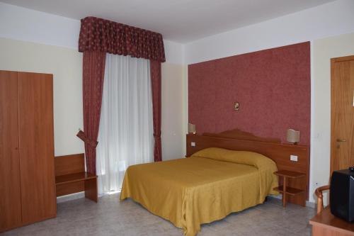 sypialnia z żółtym łóżkiem i oknem w obiekcie Hotel Dei Cappuccini w mieście San Giovanni Rotondo