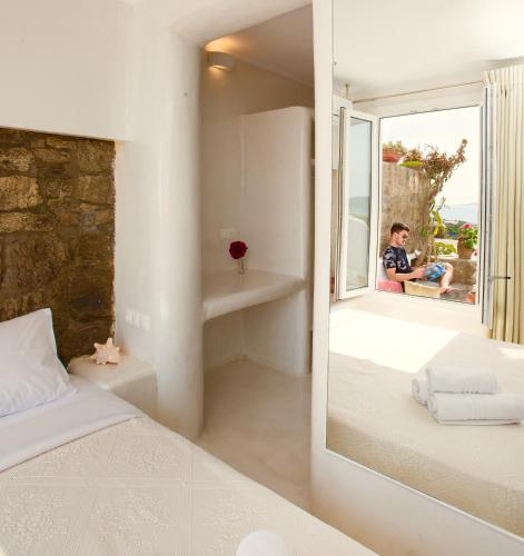 a bedroom with a mirror and a person looking out the window at Villa Elina suites and more in Agios Stefanos