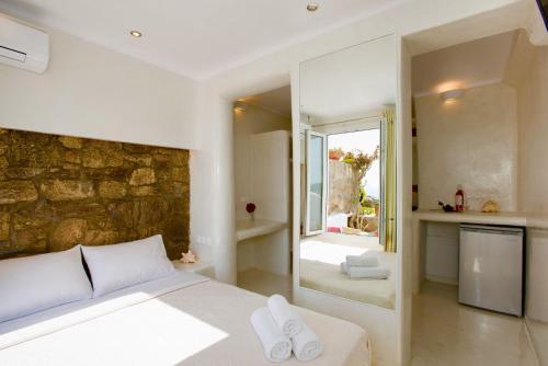 a bedroom with a white bed and a stone wall at Villa Elina suites and more in Agios Stefanos