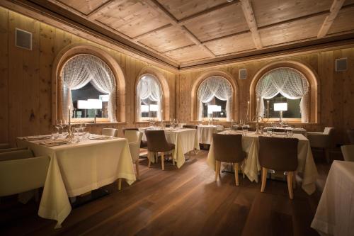 a dining room with tables and chairs and windows at Hotel San Lorenzo in Bormio