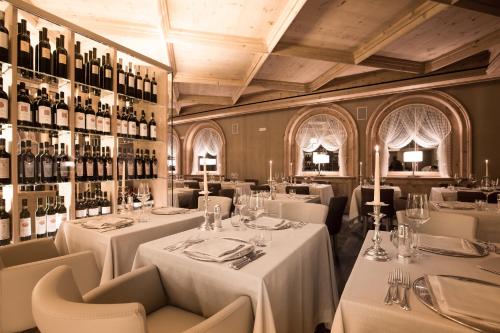 a restaurant with white tables and bottles of wine at Hotel San Lorenzo in Bormio