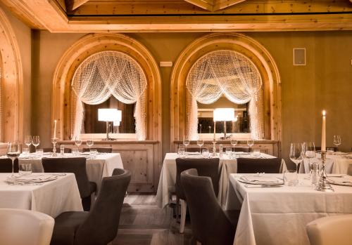 a restaurant with white tables and chairs and two windows at Hotel San Lorenzo in Bormio