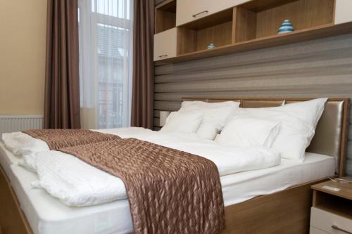 um quarto com uma cama grande com lençóis brancos e almofadas em Ditta Panzio em Debrecen