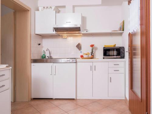 cocina blanca con armarios blancos y microondas en Cozy Apartment in Herrischried near Black Forest en Herrischried