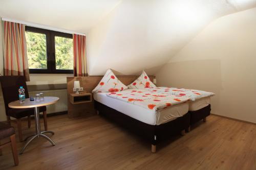 a bedroom with a bed and a table and a window at Waldhotel Albachmühle mit Albacher Stuben in Wasserliesch