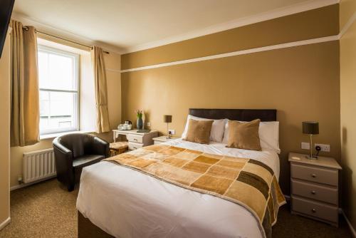 a bedroom with a large bed and a chair at The Longboat Inn in Penzance