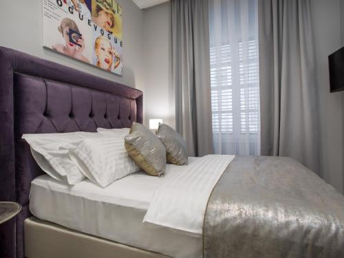 uma cama com lençóis brancos e almofadas num quarto em Tailor Two-Bedroom Suite em Dubrovnik