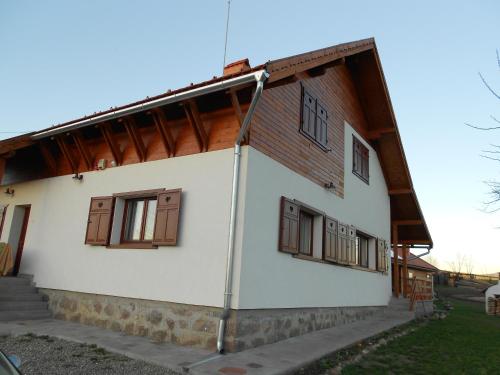 a white building with brown windows on it at Eszter Guesthouse in Sîncrăieni