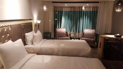 a hotel room with two beds and a table and chairs at Hotel Peninsula Redpine in Mumbai