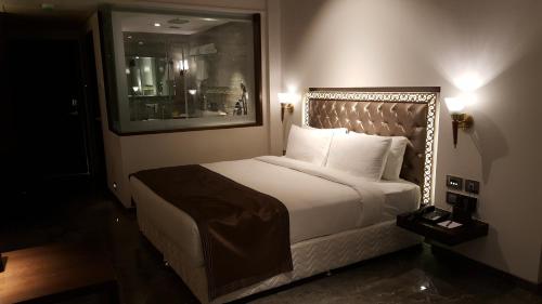 a bedroom with a white bed with a large headboard at Hotel Peninsula Redpine in Mumbai