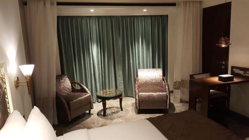a hotel room with a bed and a chair and a window at Hotel Peninsula Redpine in Mumbai