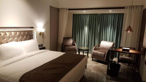 a hotel room with a bed and a desk and a window at Hotel Peninsula Redpine in Mumbai