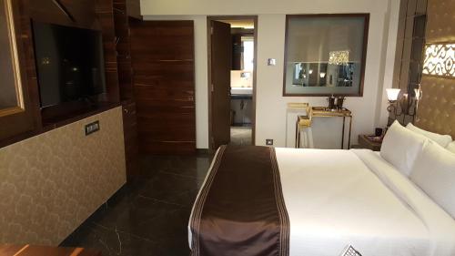 a bedroom with a large bed and a television at Hotel Peninsula Redpine in Mumbai