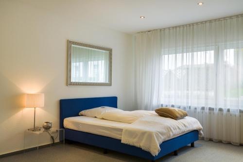 a bedroom with a blue bed and a window at Hotel Schewe in Löhne