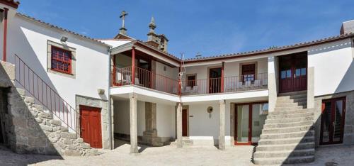 a large white building with a red door and stairs at Casa da Torre in Sobrosa