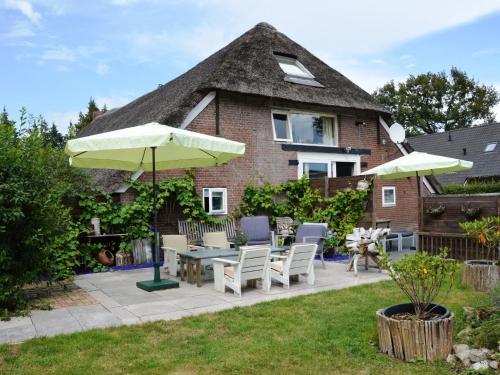 een patio met een tafel en stoelen en een parasol bij Beautiful farmhouse in Wapse with fenced garden in Wapse