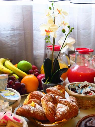 a table with pastries and fruit and a vase with flowers at Sleep And Fly Rome Airport in Fiumicino