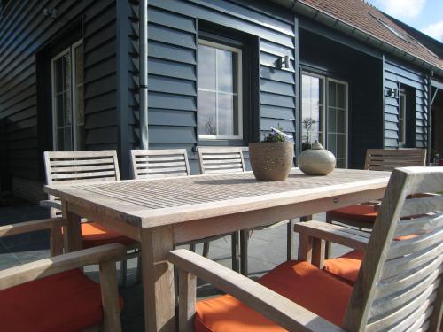 ZuidzandeにあるStylish Holiday Home in Zuidzande with Saunaの木製テーブルと椅子付きのパティオ