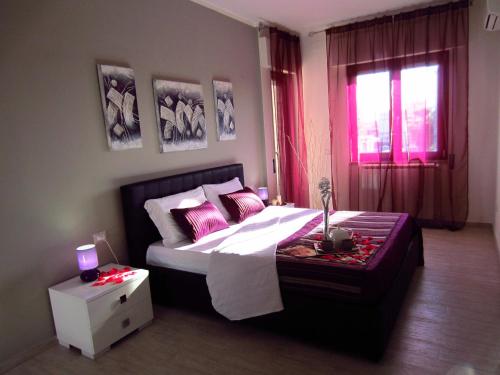 a bedroom with a bed with pink pillows and a window at Sleep And Fly Rome Airport in Fiumicino