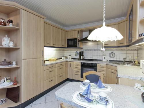 a kitchen with wooden cabinets and a chandelier at Apartment near the forest in Hullersen in Einbeck