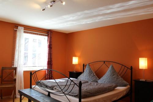 Schlafzimmer mit orangefarbenen Wänden und einem Bett mit Kissen in der Unterkunft Altstadt-Ferienwohnung in Füssen