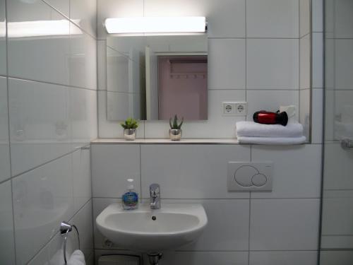 a white bathroom with a sink and a mirror at Apartments Jahnstraße in Düsseldorf