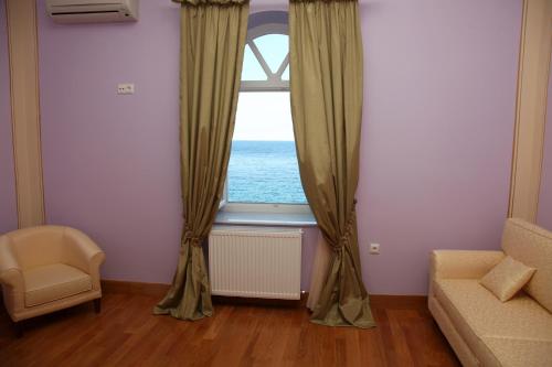 a living room with a window with a view of the ocean at Apollonion Palace in Ermoupoli