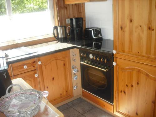 una cocina con armarios de madera y horno negro en North Sea Holiday Home in Horumersiel with Terrace, Barbecue en Bremke